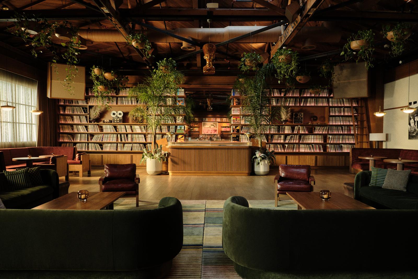 Salon № 01 in Los Angeles — a record-lined listening room with hanging plants, low lighting, and seating arranged around a central bar.